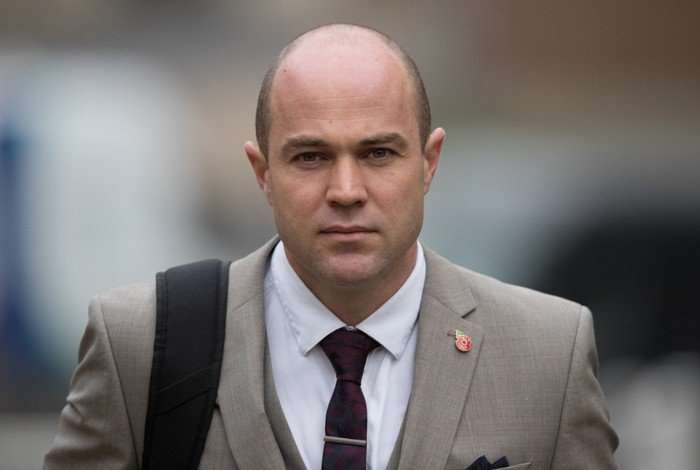 Emile Cilliers wearing a tan suit looking seriously ahead.