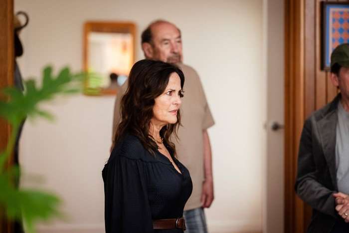 Austin Gia Carides as Mel, standing sideways to the camera