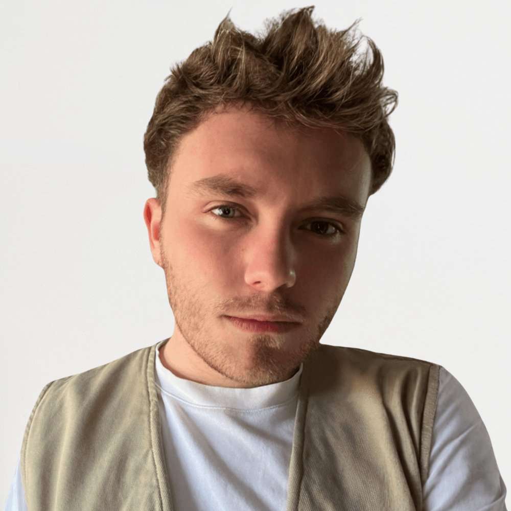 Headshot Michael Adams wearing a white t-shirt and beige gilet against a white background