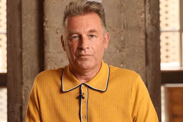 Chris Packham wearing a mustard yellow polo shirt, looking ahead.