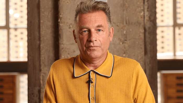 Master Sequence - 07192025.00_01_02_12.Still026 Chris Packham wearing a mustard yellow polo shirt, looking ahead.