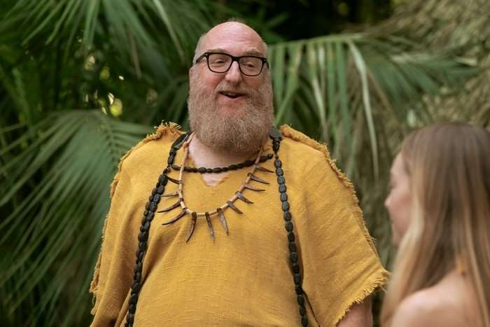 brian-posehn-stuart-fails-to-save-universe Brian Posehn as Bert Kibbler, standing in a forest wearing a yellow t-shirt and necklace made of teeth.