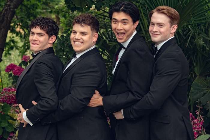 In this image from Heartstopper Forever, Charlie, Isaac, Tao and Nick wear black tuxedos and line up together for a joyful photo at their end of school prom