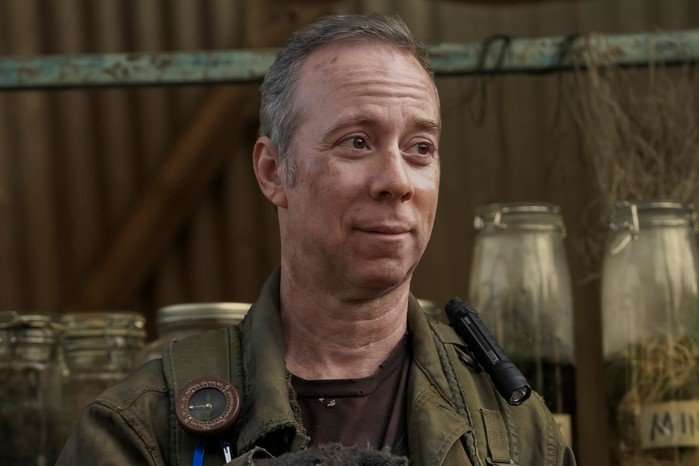 kevin-sussman-stuart-fails-to-save-universe Kevin Sussman as Stuart Bloom standing outside in a khaki cargo uniform, looking at someone expectantly.
