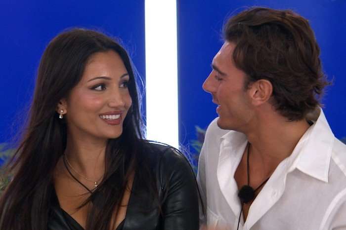 Love Island S13 Jasmine and Lorenzo sat next to each other smiling at one another.