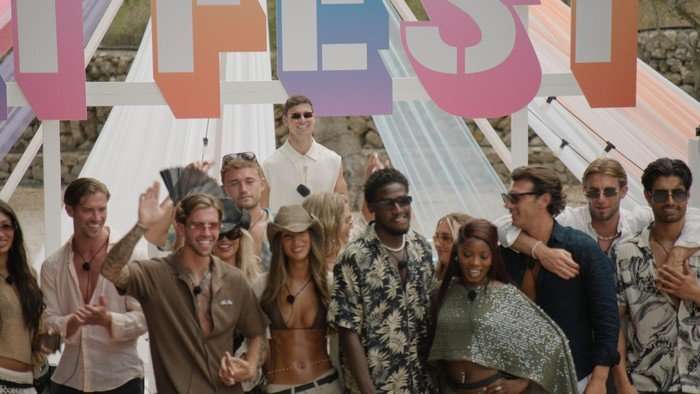 Love Island S13 A group of men and woman all stood in festival attire smiling and laughing ahead.