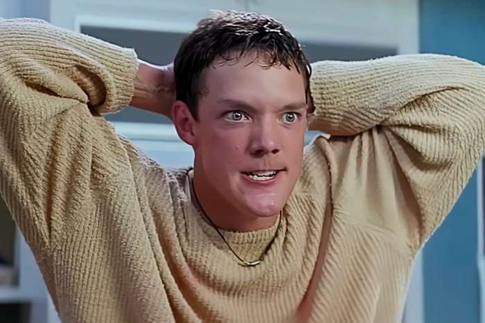 Matthew Lillard as Stu Macher in Scream Matthew Lillard as Stu Macher in Scream, wearing a cream jumper, with his hands behind his head and looking crazed.