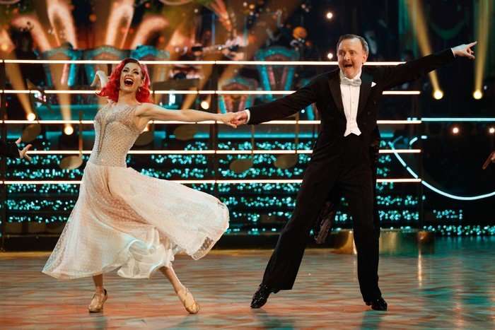 Chris McCausland and Dianne Buswell holding each other's hand, dancing and smiling.